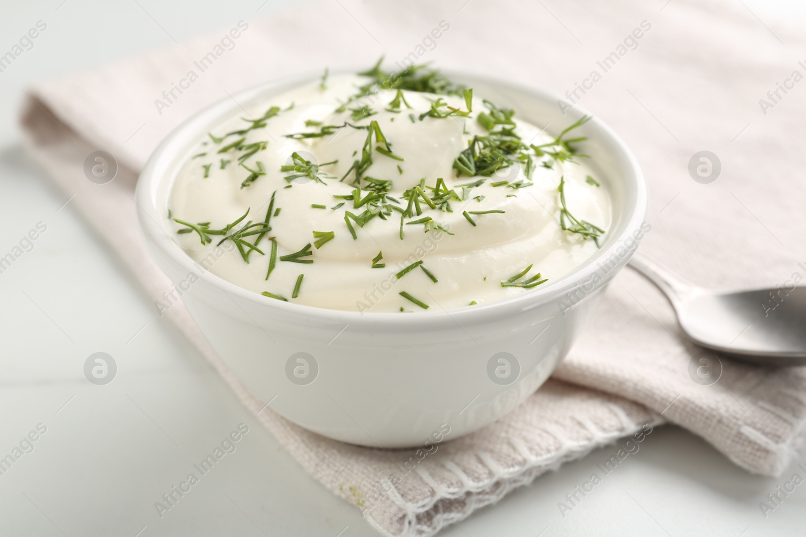 Photo of Delicious yogurt in bowl and dill on white marble table, closeup