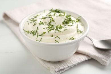 Photo of Delicious yogurt in bowl and dill on white marble table, closeup
