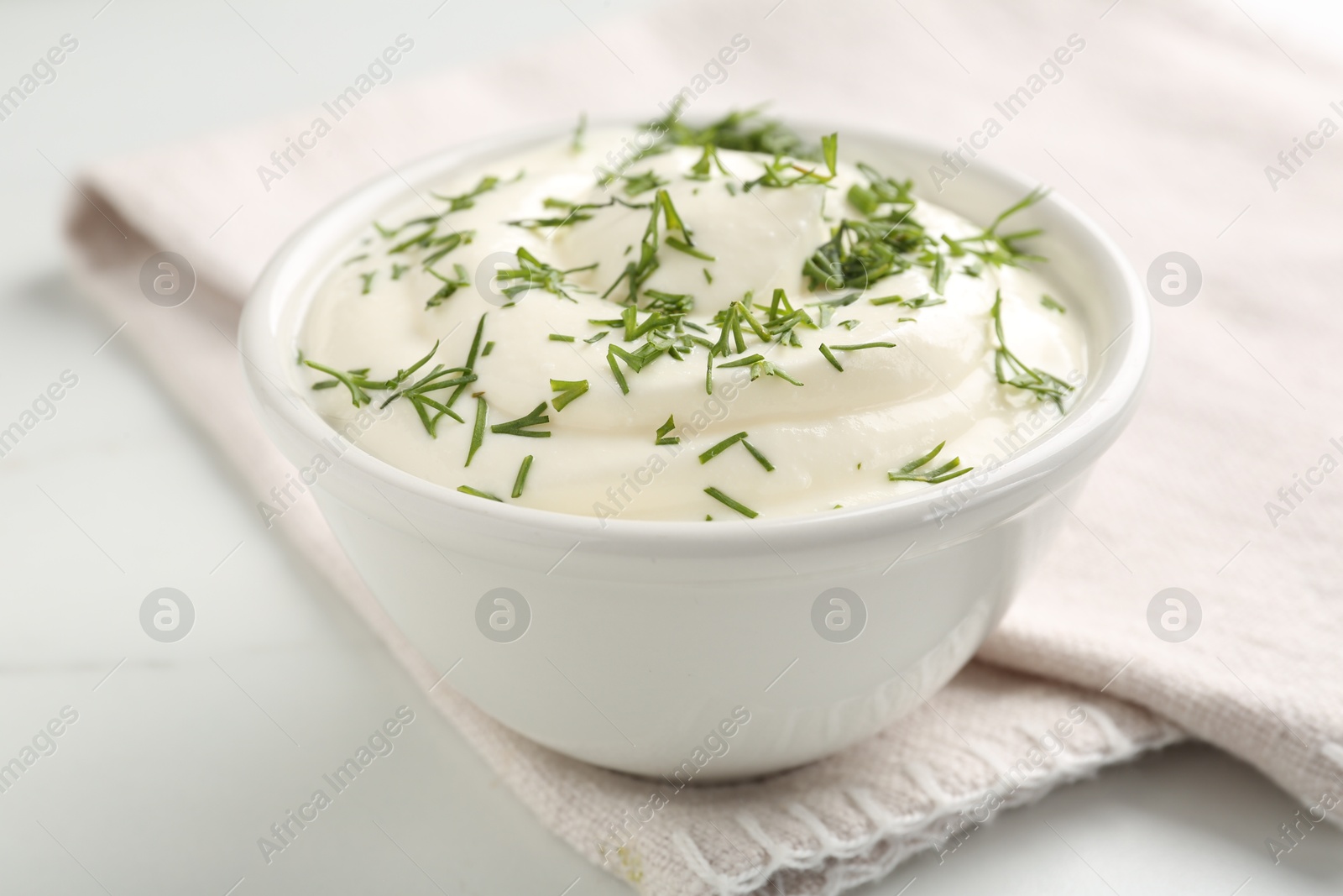 Delicious yogurt in bowl and dill on white marble table, closeup Photo of Delicious yogurt in bowl and dill on white marble table, closeup