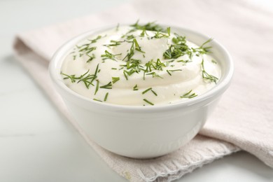 Photo of Delicious yogurt in bowl and dill on white marble table, closeup