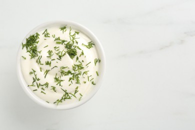 Photo of Delicious yogurt in bowl and dill on white marble table, top view. Space for text