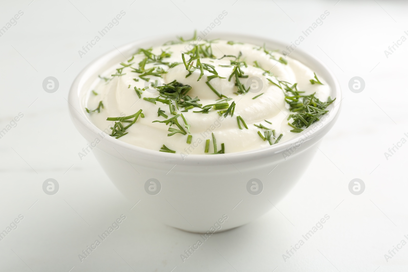 Photo of Delicious yogurt in bowl and dill on white marble table, closeup
