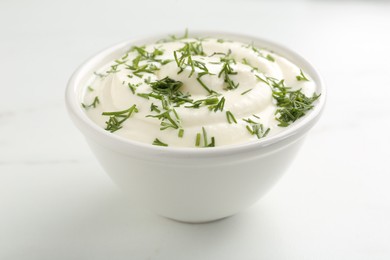 Photo of Delicious yogurt in bowl and dill on white marble table, closeup