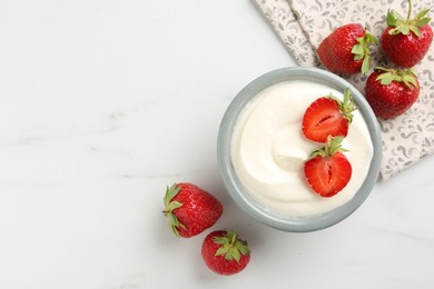 Photo of Delicious yogurt in bowl and strawberries on white marble table, flat lay. Space for text