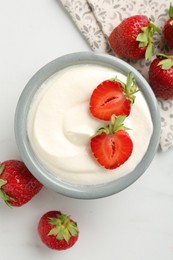 Photo of Delicious yogurt in bowl and strawberries on white marble table, flat lay