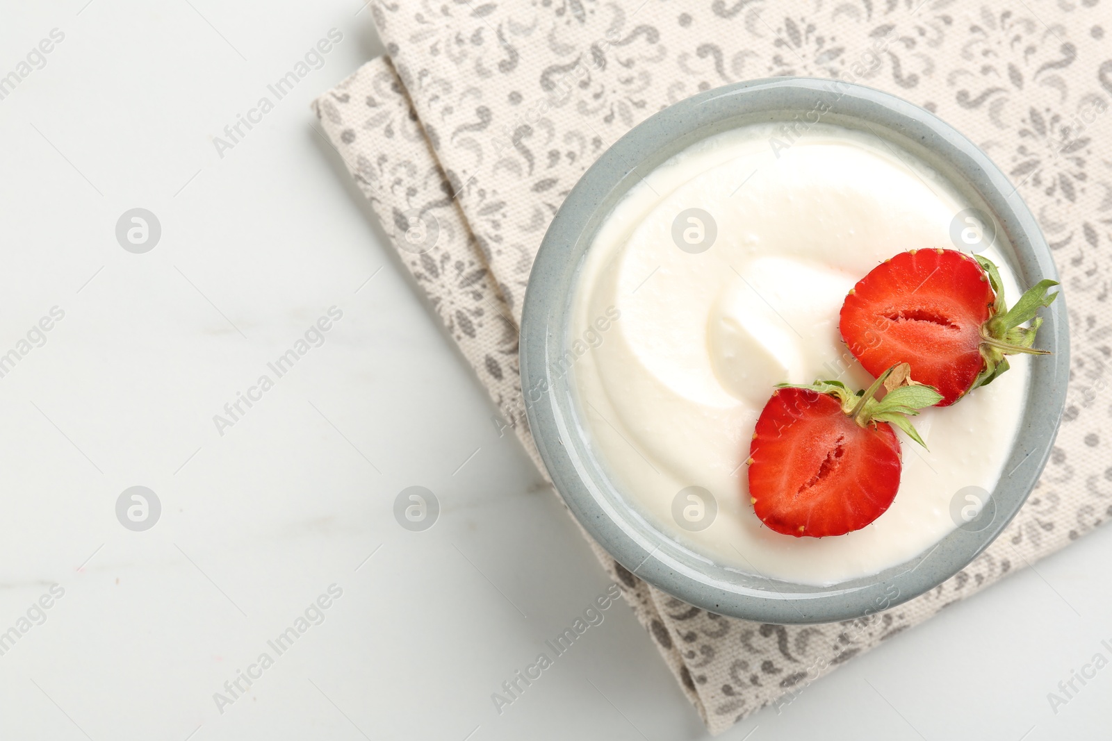 Delicious yogurt in bowl and strawberries on white marble table, top view. Space for text Photo of Delicious yogurt in bowl and strawberries on white marble table, top view. Space for text