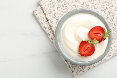 Photo of Delicious yogurt in bowl and strawberries on white marble table, top view. Space for text