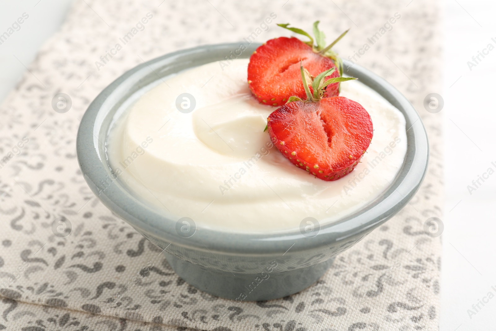 Delicious yogurt in bowl and strawberries on table, closeup Photo of Delicious yogurt in bowl and strawberries on table, closeup
