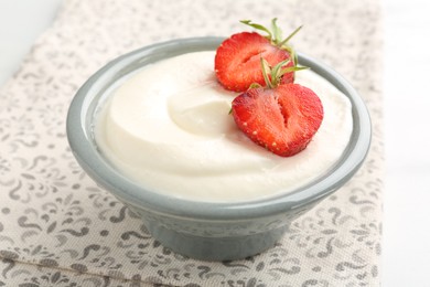 Photo of Delicious yogurt in bowl and strawberries on table, closeup