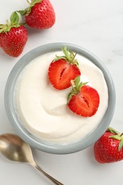 Photo of Delicious yogurt in bowl, strawberries and spoon on white marble table, flat lay