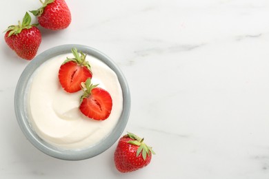 Photo of Delicious yogurt in bowl and strawberries on white marble table, flat lay. Space for text