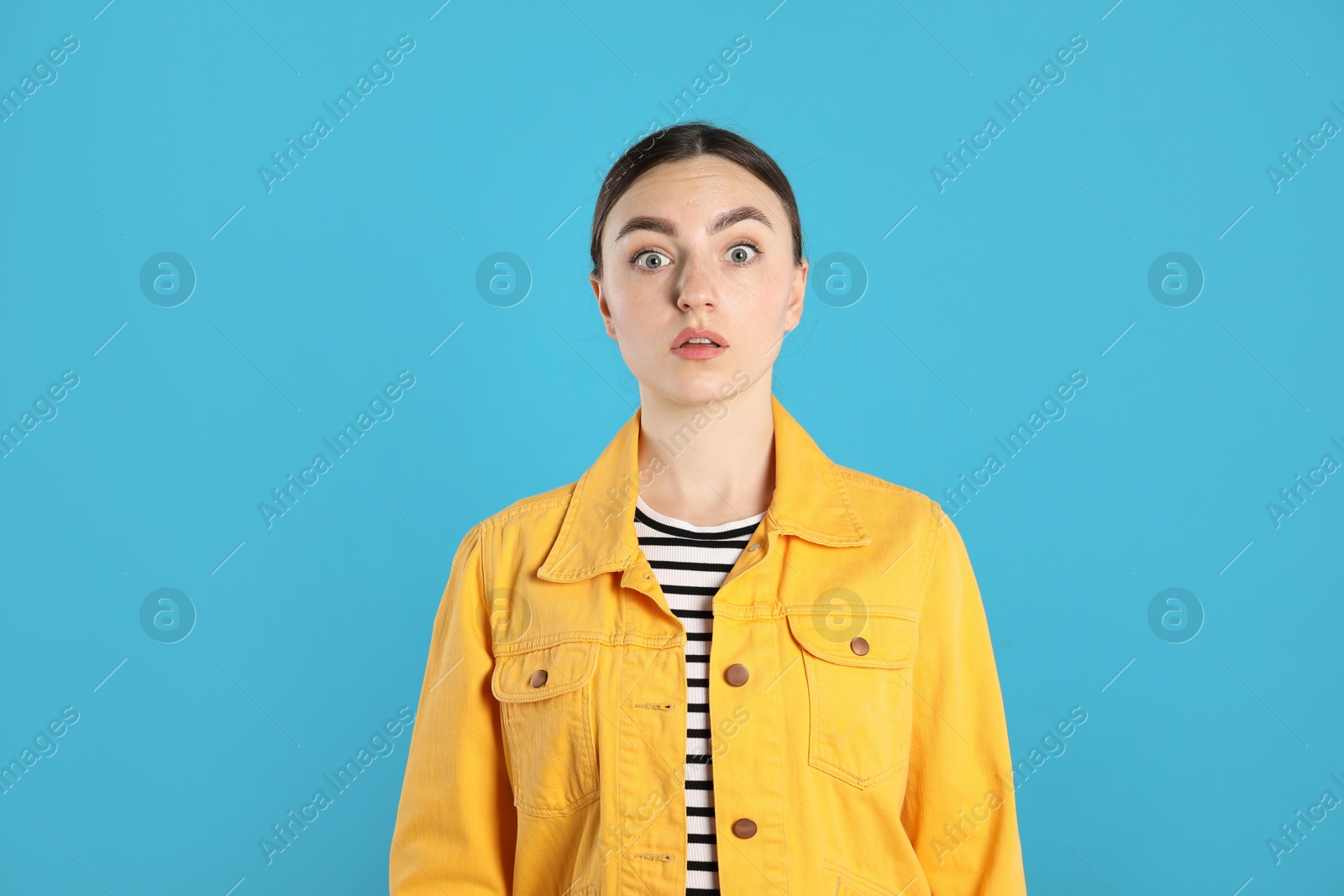Portrait of shocked woman on light blue background Photo of Portrait of shocked woman on light blue background