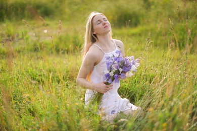 Photo of Beautiful woman with bouquet of wildflowers enjoying sunny day in meadow