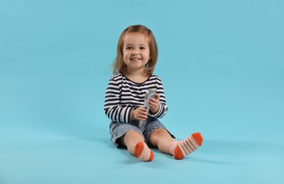 Photo of Cute little girl with microphone on light blue background