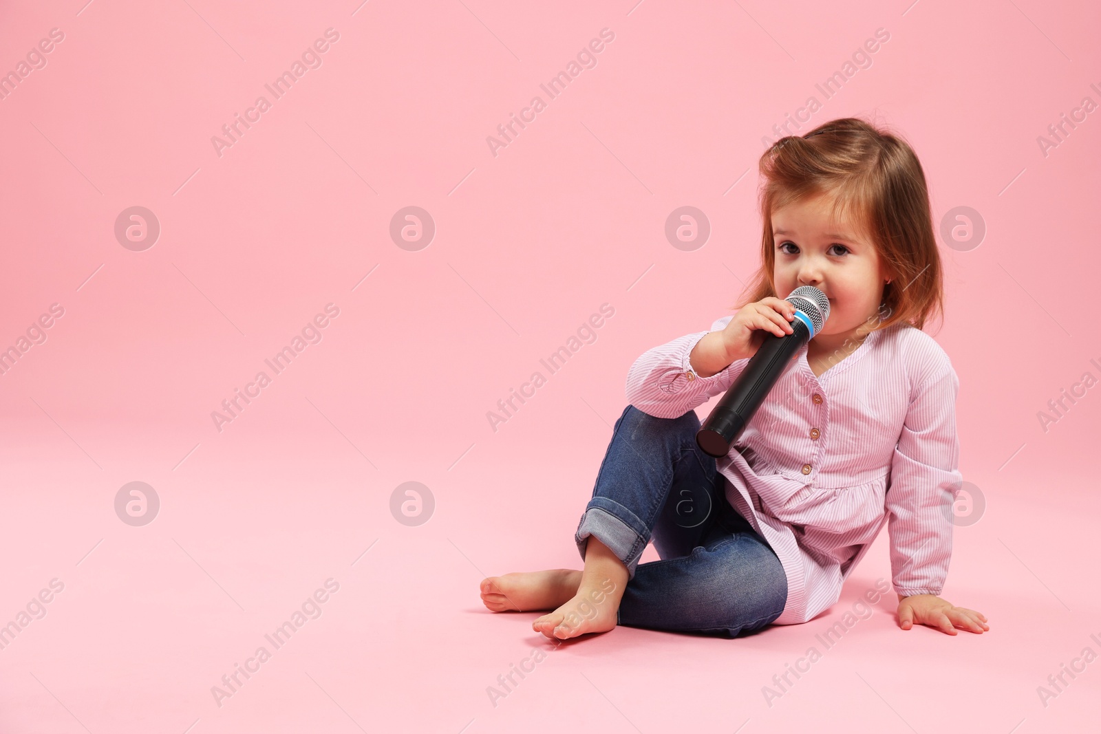 Cute little girl with microphone on pink background, space for text Photo of Cute little girl with microphone on pink background, space for text