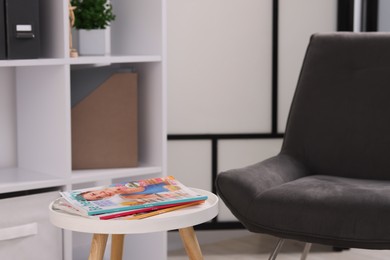 Photo of Different trendy magazines on white table and armchair indoors