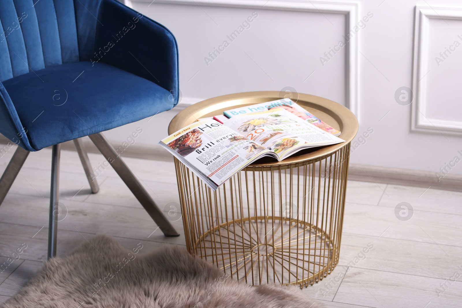 Photo of Different trendy magazines and armchair on table indoors