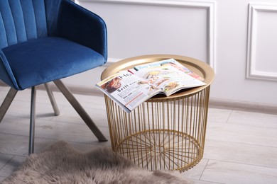 Photo of Different trendy magazines and armchair on table indoors