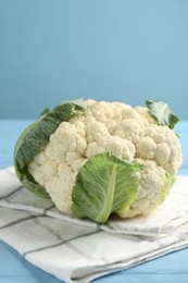 Photo of Whole cauliflower on light blue wooden table, closeup