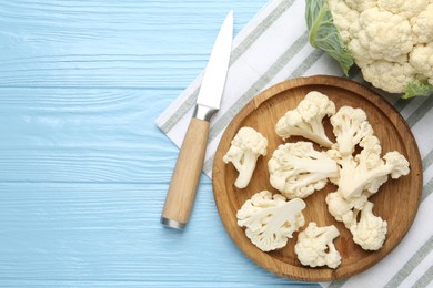 Photo of Pieces of cauliflower and knife on light blue wooden table, flat lay. Space for text