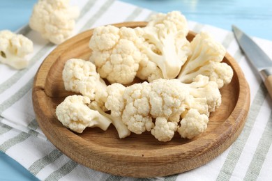 Photo of Pieces of cauliflower and knife on light blue wooden table, closeup
