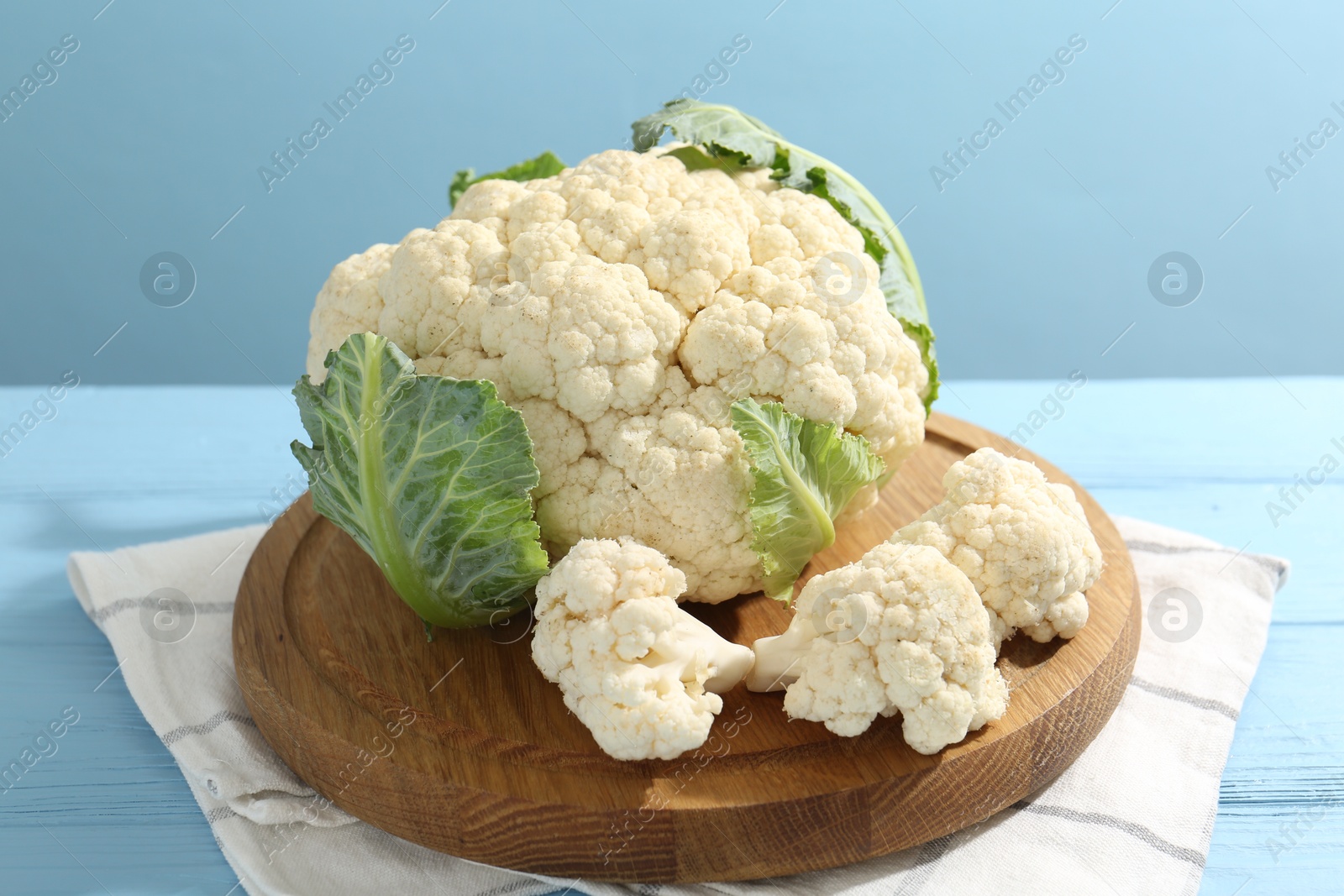Photo of Raw cauliflower on light blue wooden table, closeup