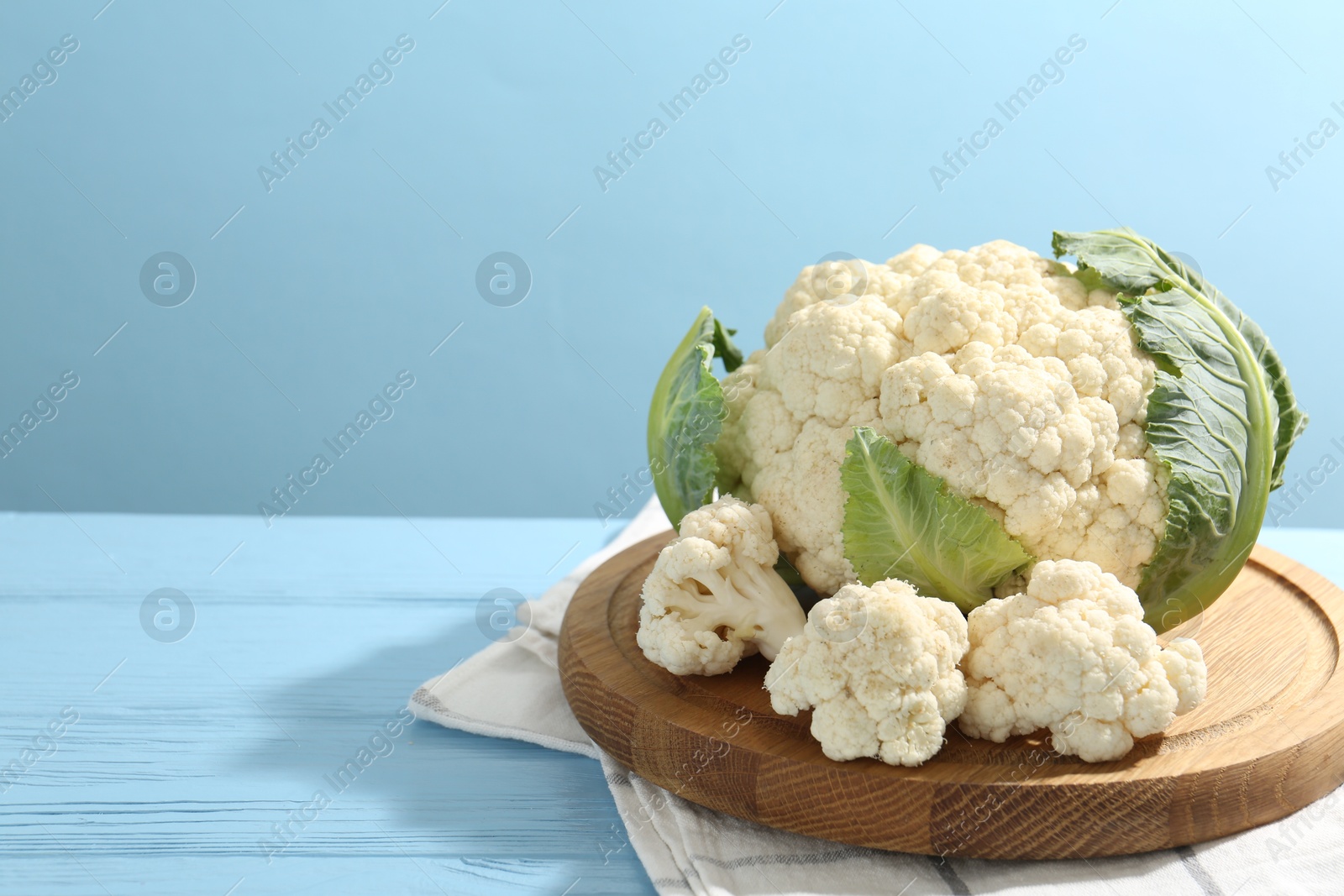 Photo of Raw cauliflower on light blue wooden table. Space for text