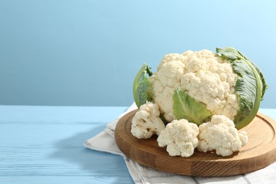 Photo of Raw cauliflower on light blue wooden table. Space for text
