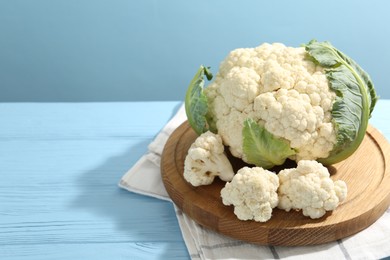 Photo of Raw cauliflower on light blue wooden table. Space for text