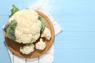 Photo of Raw cauliflower on light blue wooden table, top view. Space for text