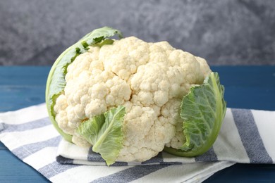 Photo of Whole cauliflower on blue wooden table, closeup