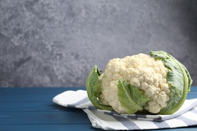 Photo of Whole raw cauliflower on blue wooden table. Space for text