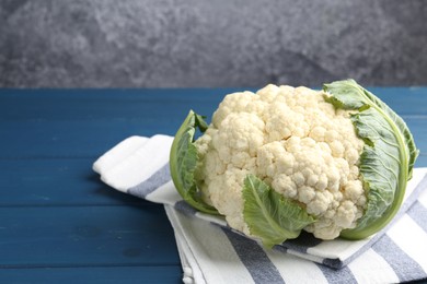 Photo of Whole raw cauliflower on blue wooden table. Space for text
