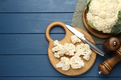 Photo of Pieces of cauliflower, knife and spices on blue wooden table, flat lay. Space for text
