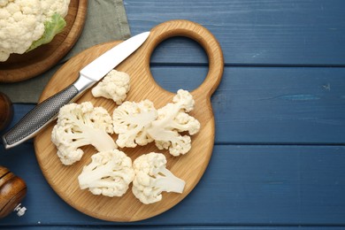 Photo of Pieces of cauliflower, knife and spices on blue wooden table, flat lay. Space for text