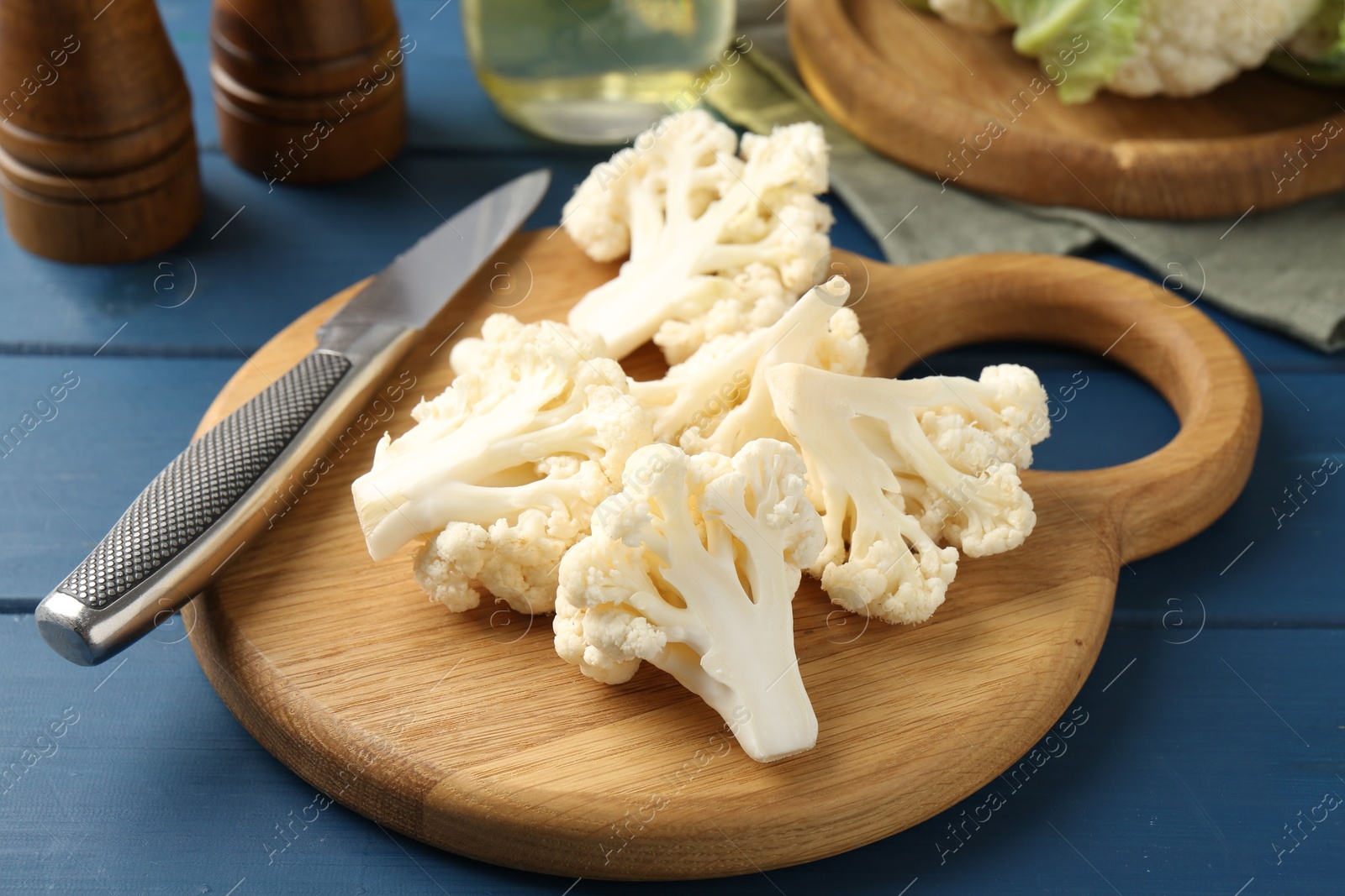 Pieces of cauliflower, knife and spices on blue wooden table, closeup Photo of Pieces of cauliflower, knife and spices on blue wooden table, closeup
