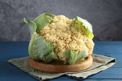 Photo of Whole cauliflower on blue wooden table, closeup