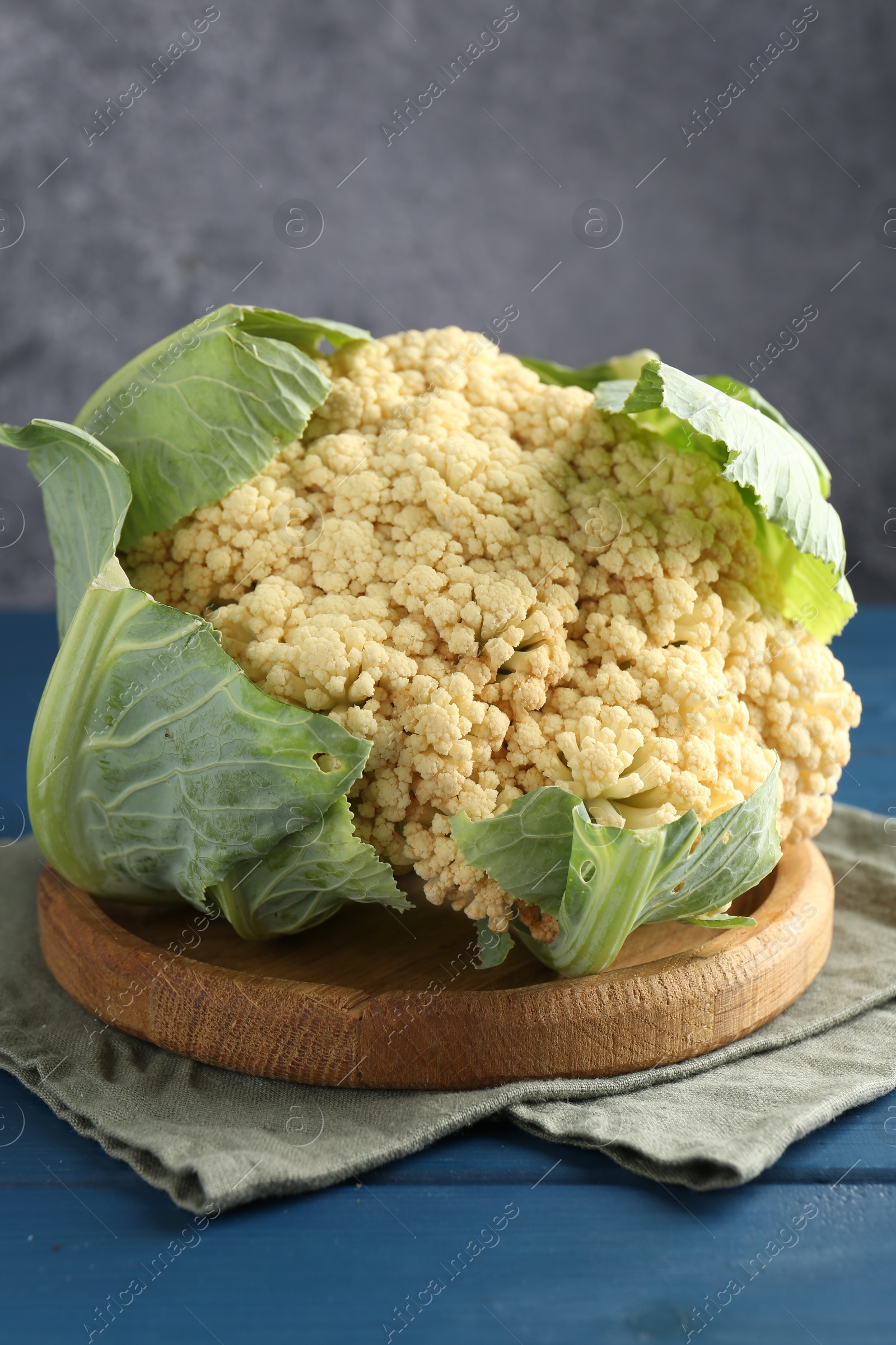 Photo of Whole cauliflower on blue wooden table, closeup
