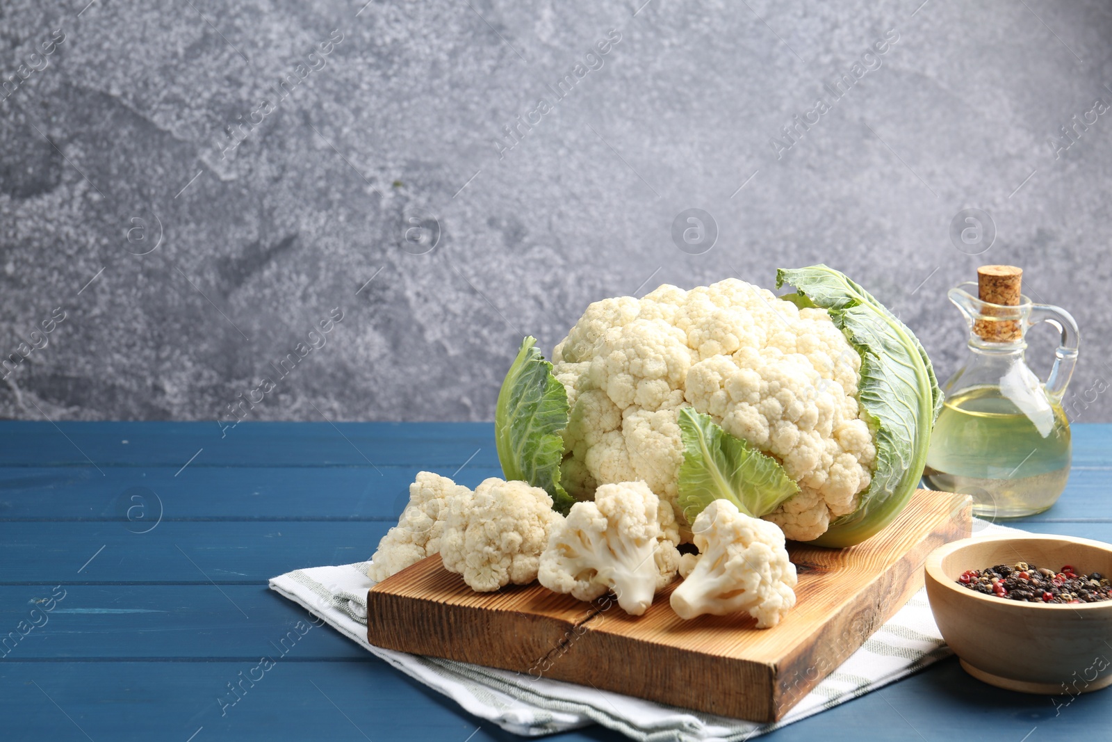 Raw cauliflower, peppercorns and oil on blue wooden table. Space for text Photo of Raw cauliflower, peppercorns and oil on blue wooden table. Space for text