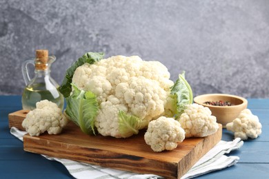 Photo of Raw cauliflower, peppercorns and oil on blue wooden table