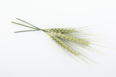 Photo of Many green wheat spikes on white background, top view
