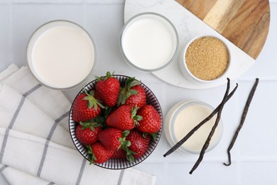 Photo of Different ingredients for panna cotta. Milk, sugar, vanilla and strawberries on white tiled table, flat lay