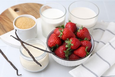 Photo of Different ingredients for panna cotta. Milk, sugar, vanilla and strawberries on white tiled table, closeup