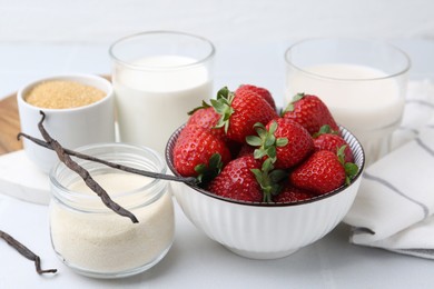 Photo of Different ingredients for panna cotta. Milk, sugar, vanilla and strawberries on white tiled table, closeup