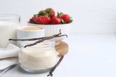 Photo of Different ingredients for panna cotta. Milk, sugar, vanilla and strawberries on white tiled table, closeup. Space for text