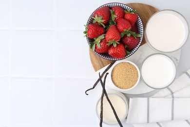 Photo of Different ingredients for panna cotta. Milk, sugar, vanilla and strawberries on white tiled table, flat lay. Space for text