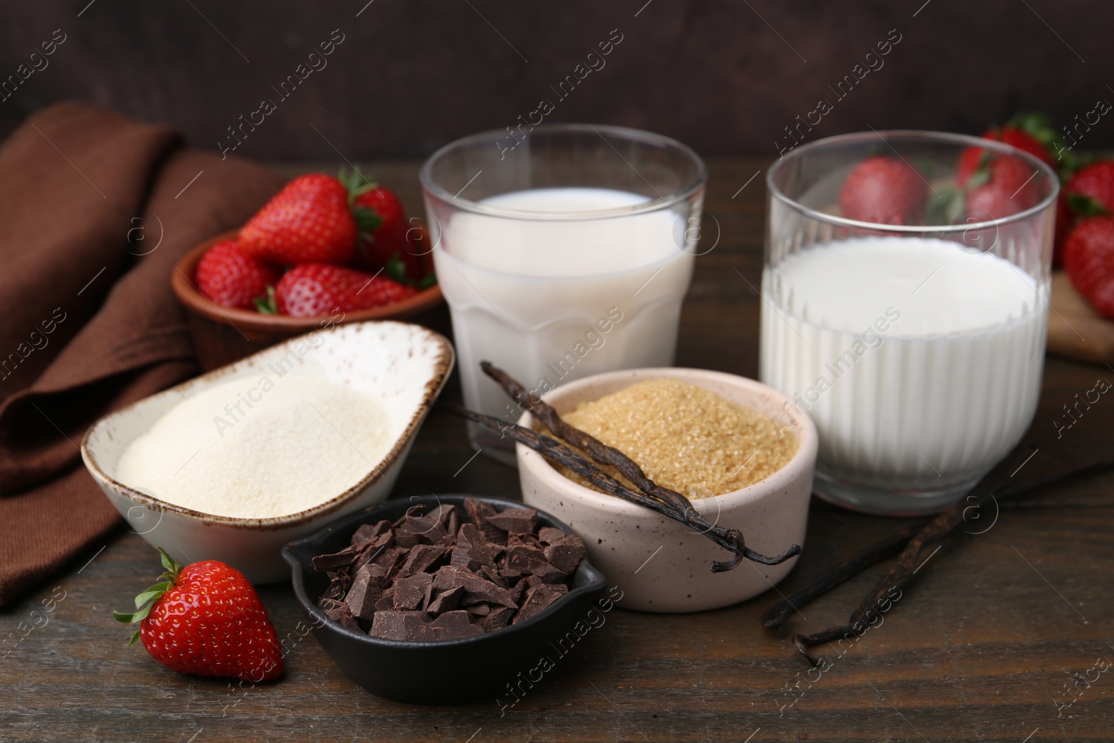 Different ingredients for panna cotta. Milk, sugar, vanilla, chocolate and strawberries on wooden table, closeup Photo of Different ingredients for panna cotta. Milk, sugar, vanilla, chocolate and strawberries on wooden table, closeup