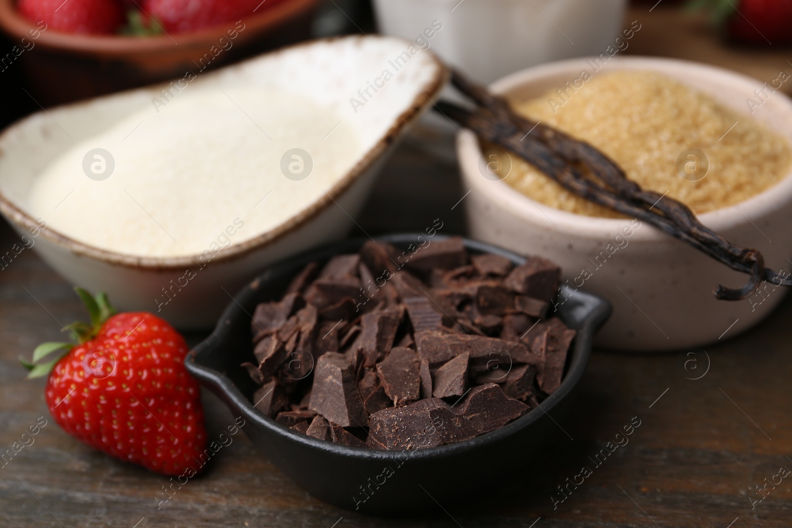 Different ingredients for panna cotta. Milk, sugar, vanilla, chocolate and strawberries on wooden table, closeup Photo of Different ingredients for panna cotta. Milk, sugar, vanilla, chocolate and strawberries on wooden table, closeup