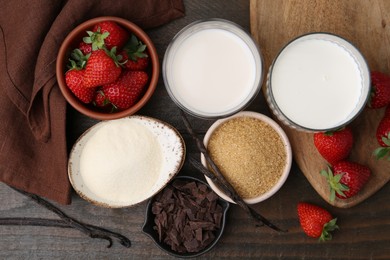 Photo of Different ingredients for panna cotta. Milk, sugar, vanilla, chocolate and strawberries on wooden table, flat lay