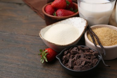 Photo of Different ingredients for panna cotta. Milk, sugar, vanilla, chocolate and strawberries on wooden table, closeup. Space for text
